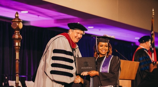 President Blake shaking hands with a graduate and handing them their degree at spring 2022 graduation.